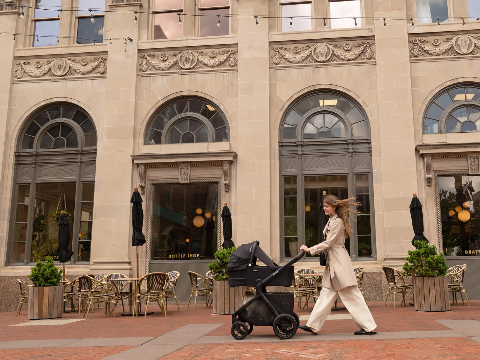 A woman pushes the DEMI icon pushchair through a plaza.