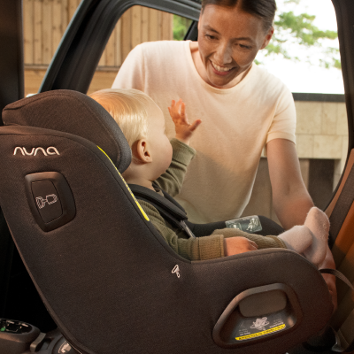 Mother smiles at toddler in car seat