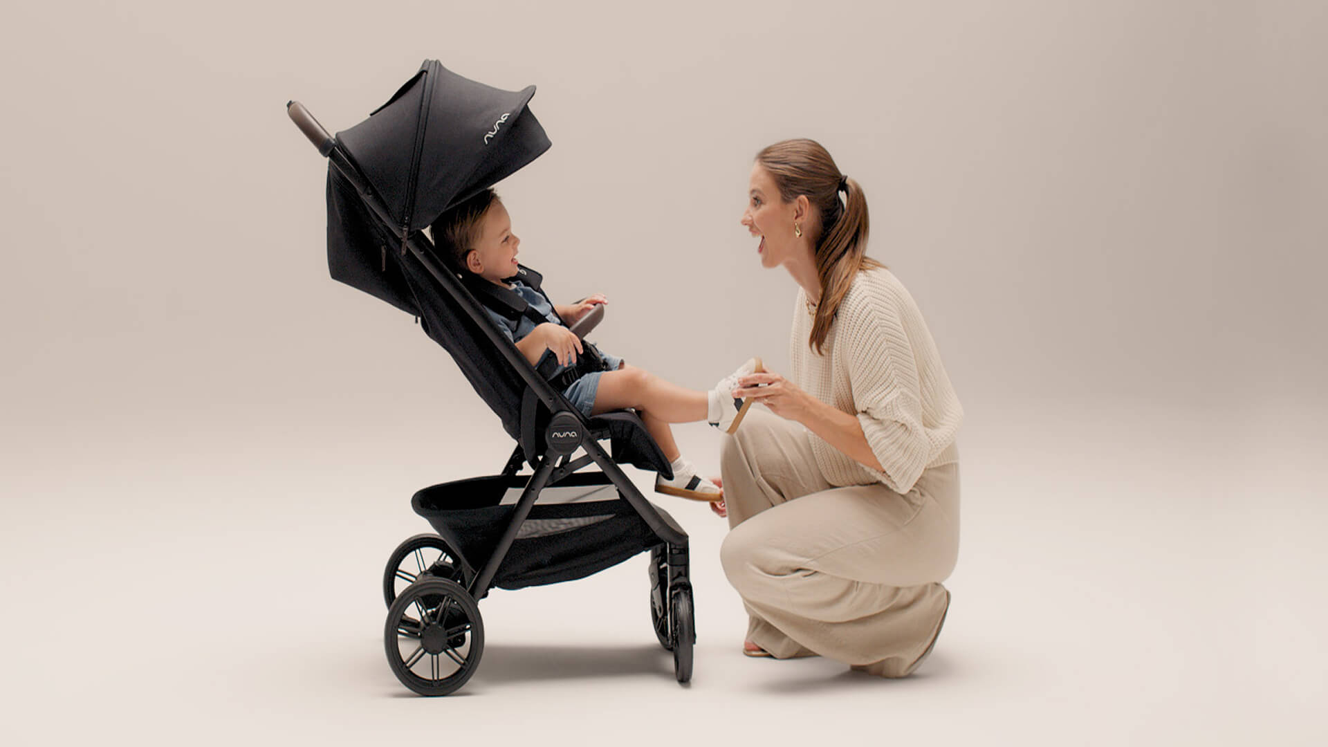Nuna TRVL urbn pushchair with toddler seated inside, laughing with his mother.