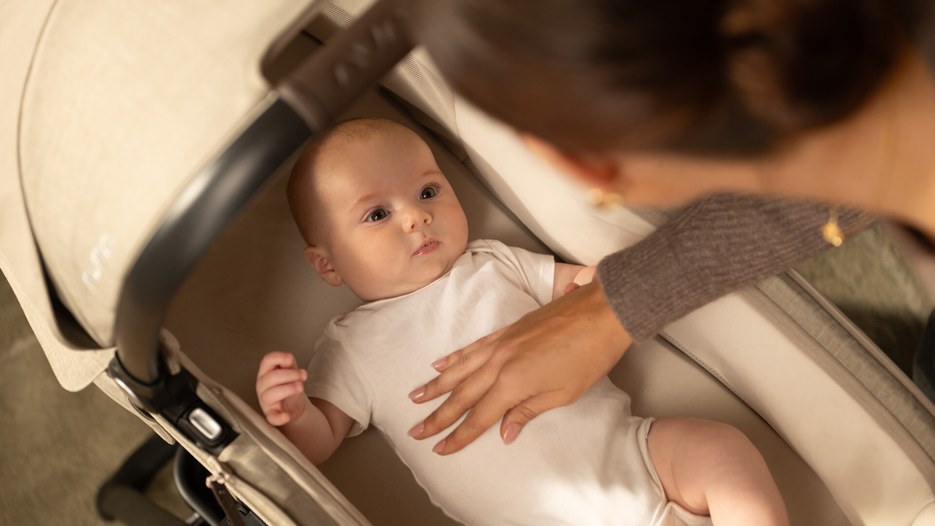 An infant peers out from the MIXX next carry cot