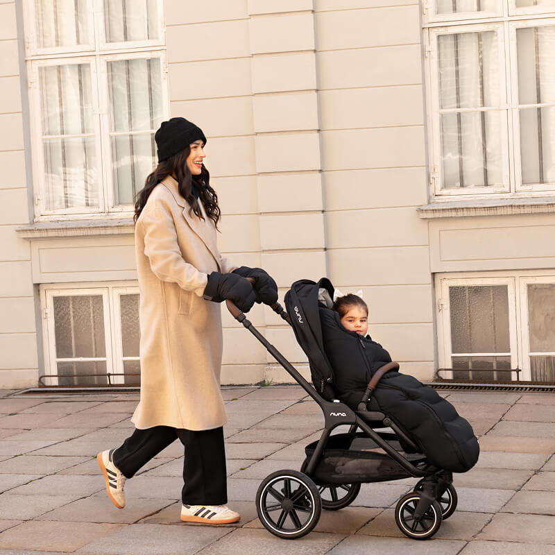 A warmly dressed woman pushes her child in the TRIVlx puschair with the TRIV lx all-in-one set accessories. 