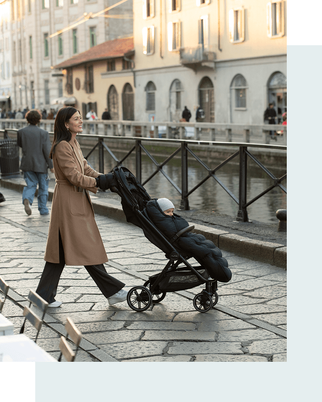 A warmly dressed woman pushes her child in the TRIVlx puschair with the Winter Stroller Set accessories. 
