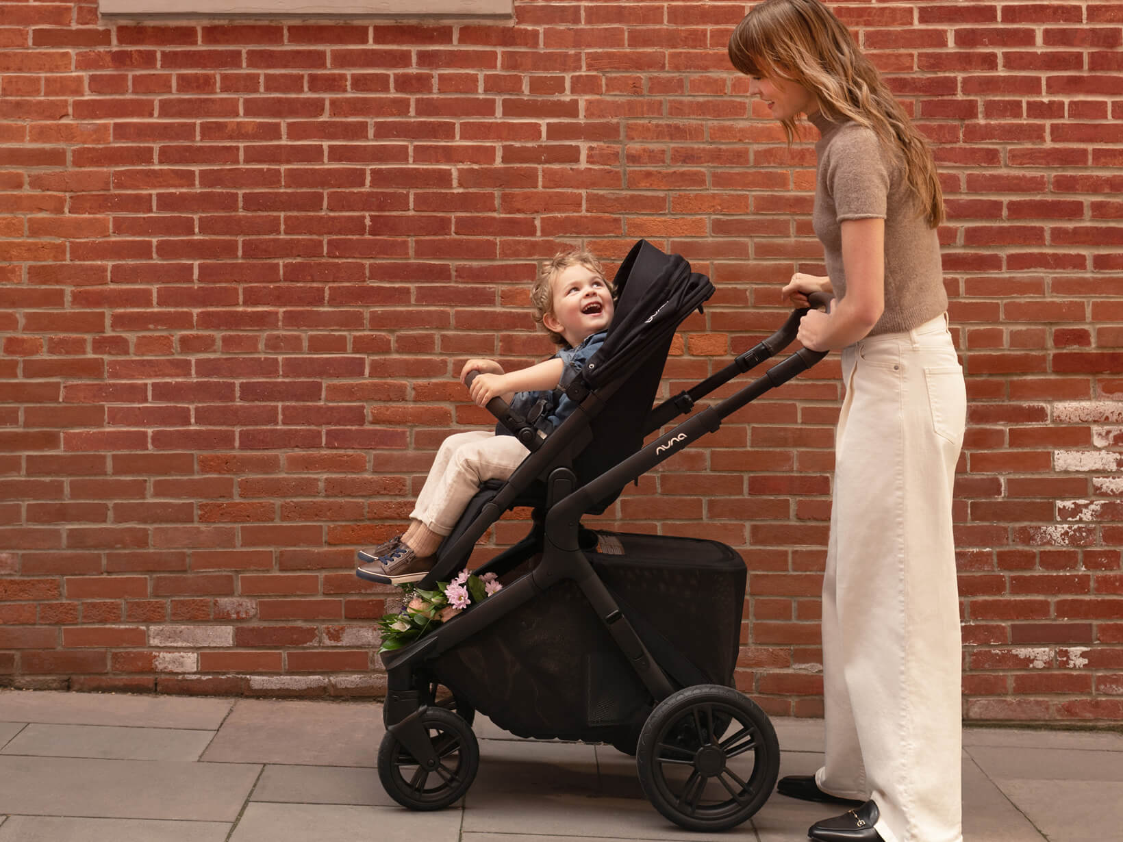 A woman smiles at her toddler in the DEMI icon pushchair.