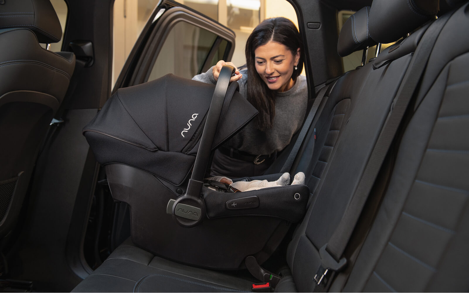 A woman places the PIPA urbn carseat into the backseat of a vehicle.