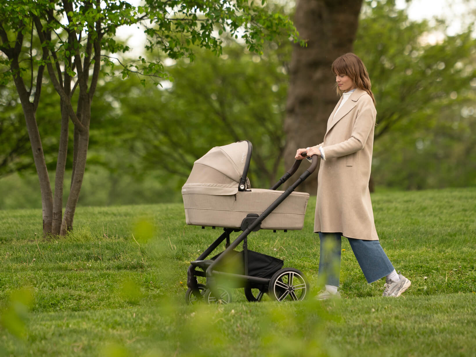 A woman pushes the MIXX next carry cot attached to the MIXX next pushchair base.