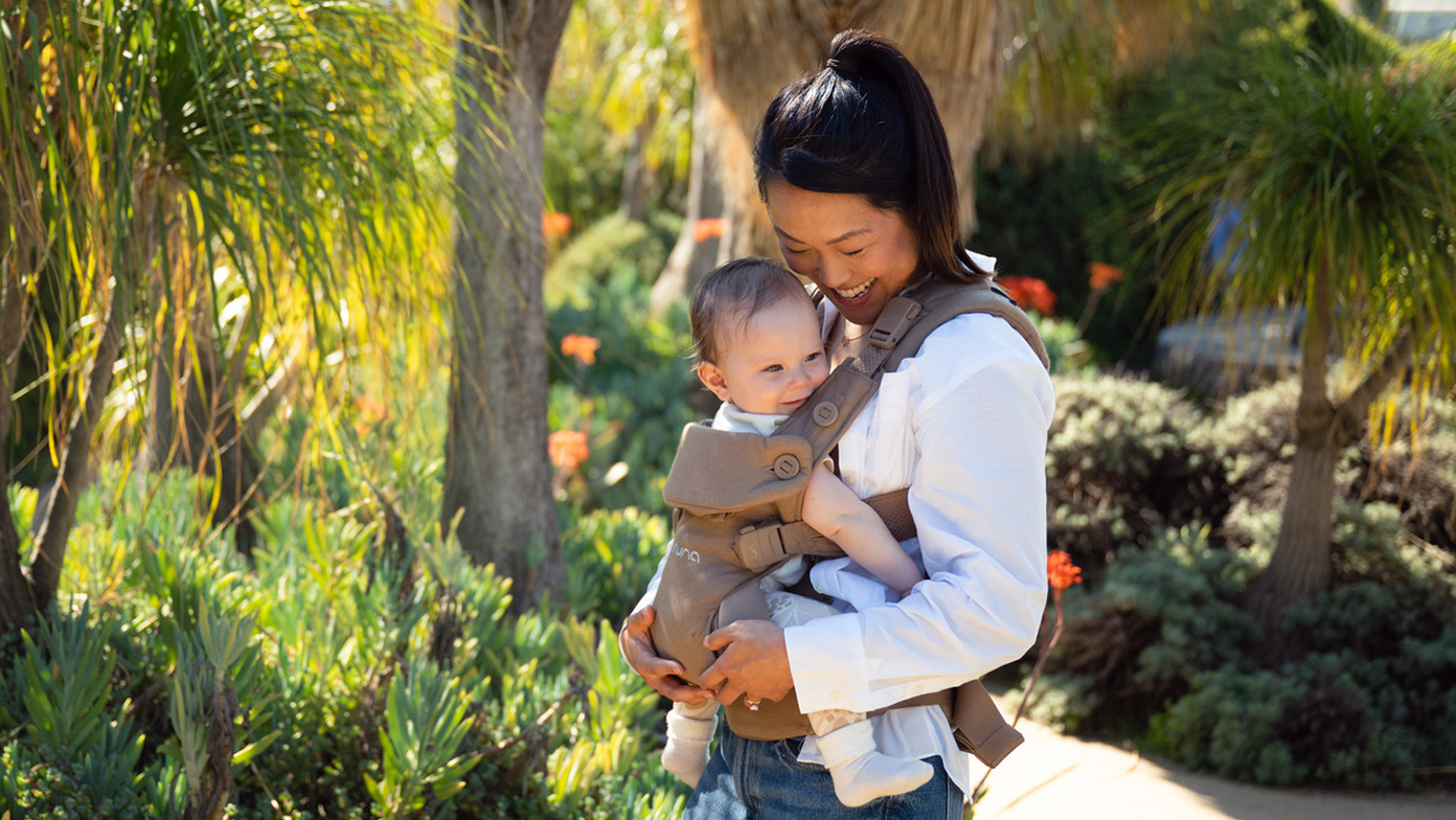 A mother wearing her baby in the Nuna CUDL Series infant carrier.
